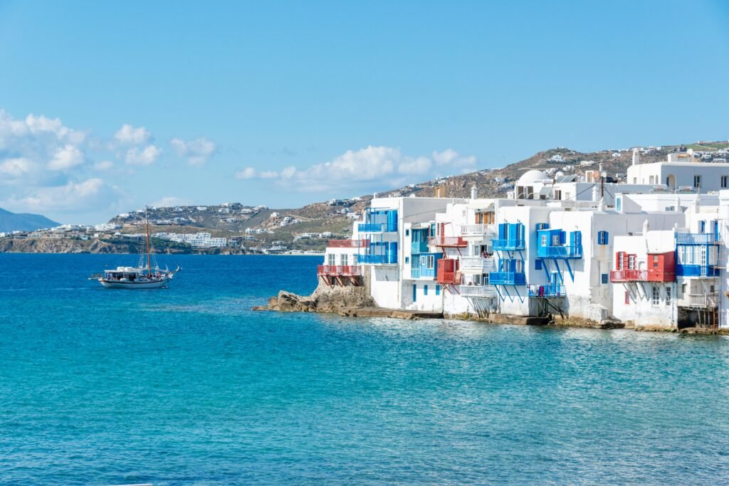 Charming white and blue houses on the Mykonos waterfront under a bright blue sky.